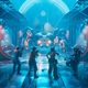 Four soldiers shoot at a giant spiderbot in a bluelit hallway in The Ascent.